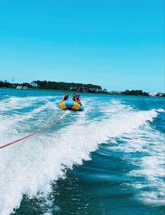 two people riding on the back of a yellow and blue boat