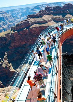 people are walking along the edge of a walkway over a canyon in grand canyon national park