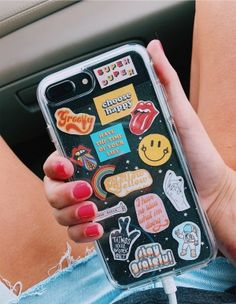 someone is holding their phone with stickers on it