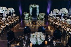 the tables are set up with black chairs and white flowers