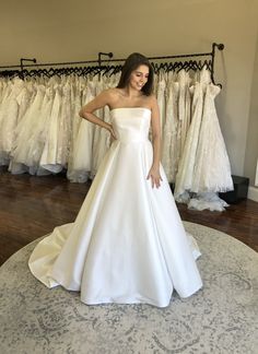 a woman standing in front of some wedding dresses