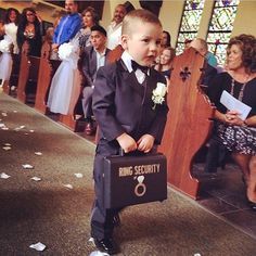 a young boy in a suit and tie holding a briefcase while people watch from the pews