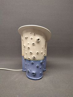 a blue and white vase with holes on it's side sitting on a gray surface