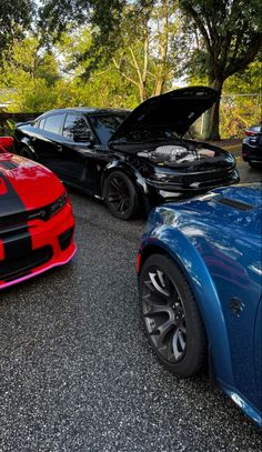 two cars parked next to each other in a parking lot with the hood up on