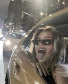 a woman sticking her tongue out in the back of a car on a city street