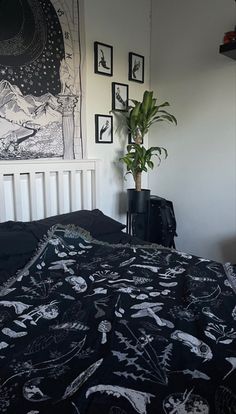 a bed with black and white bedspread next to a plant in a pot