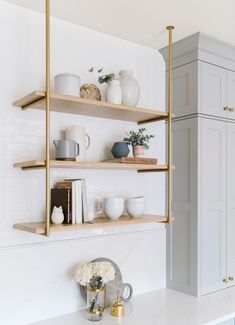 the shelves in this kitchen are filled with white dishes and vases on top of them