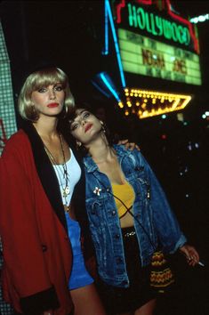 two young women standing next to each other in front of a hollywood marquee