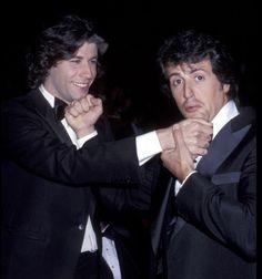 two men in tuxedos standing next to each other with their hands on their chest