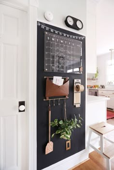 a chalkboard with calendars and magnets on it in a white kitchen area