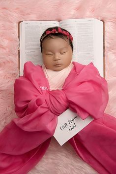 a baby doll laying on top of an open book with a gift from god tag