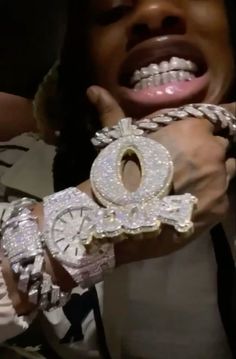 a close up of a person holding a wrist watch and wearing some chains on it