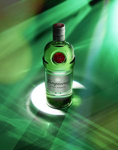 a bottle of green wine sitting on top of a white plate in front of a green background