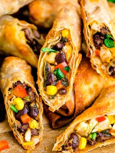 several burritos filled with beans and veggies on a wooden cutting board