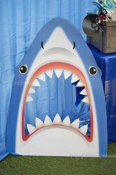 a blue and white shark tent with its mouth open, sitting on top of a green carpeted floor