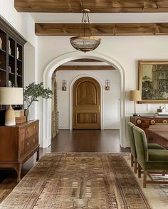 an archway leads to a formal dining room with wood flooring and wooden furniture, along with a rug on the floor