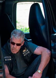 a man sitting in the back seat of a car with his hands on his knees