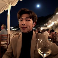 a man sitting at a table with a glass of wine in front of his face