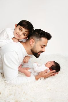 a man holding a baby while laying on top of a white rug