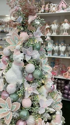 a christmas tree decorated with pastel pink and green ornaments in a store display case