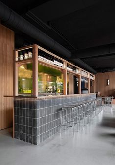 an empty bar with stools and bottles on the back wall in a dark room