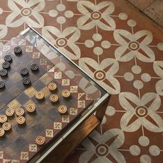 an old wooden chess set on top of a glass table with matching tile flooring