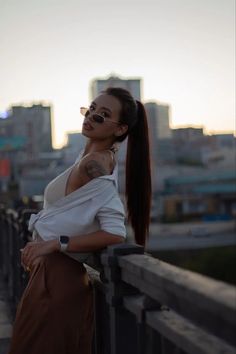 a woman standing on top of a bridge next to tall buildings