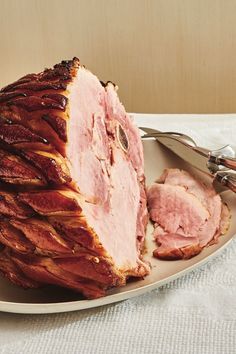 the ham is sliced and ready to be served on the plate with utensils