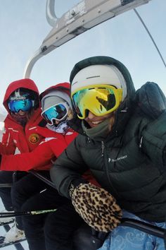 three skiers sitting in the back of a ski lift with their skis on