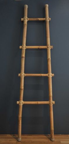 an old wooden ladder leaning against a blue wall in a room with wood flooring