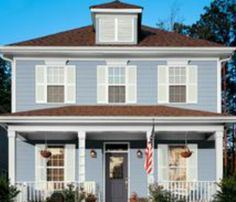 a two story house with red shutters and an american flag on the front door