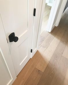 two white doors with black handles on each side and wood flooring in the background