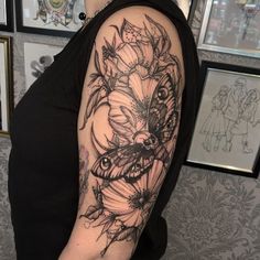 a woman with a black and white tattoo on her arm, holding a flower bouquet