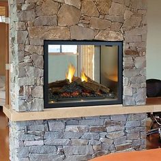 a stone fireplace in a living room with wood flooring