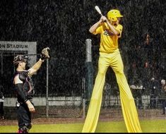 a baseball player holding a bat next to home plate in the rain with catcher and umpire behind him