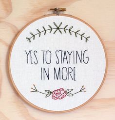 a cross stitch hoop with the words yes to staying in more