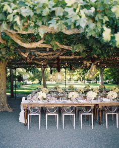 the table is set up with white flowers and greenery for an outdoor wedding reception