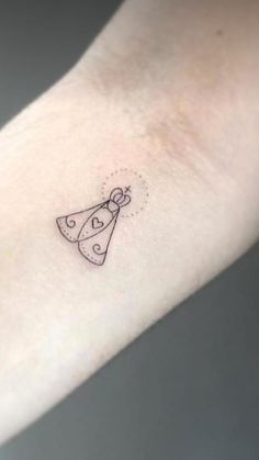 a small tattoo on the wrist of a woman's arm with a bell and bow