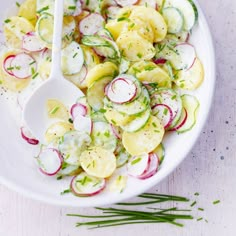 a white bowl filled with cucumber and radishes on top of a table