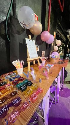 a wooden table topped with lots of different types of balloons and confetti on top of it