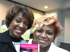 two women smiling and holding up a book