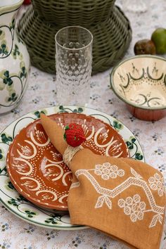 a table topped with plates and bowls covered in cloths next to cups filled with fruit