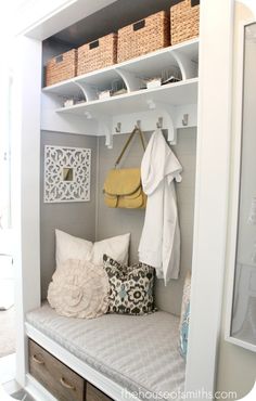 a white closet filled with lots of pillows and clothes hanging on the wall next to a coat rack