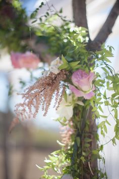 flowers and greenery are hanging from a tree