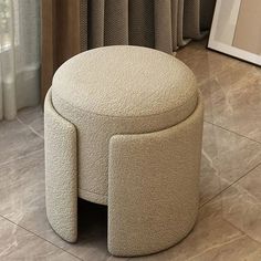 a white ottoman sitting on top of a tile floor next to a window with curtains