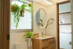 a bathroom with a sink, mirror and plants on the window sill in it