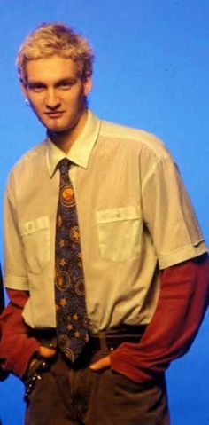 a man in a shirt and tie is standing with his hands on his hips while looking at the camera