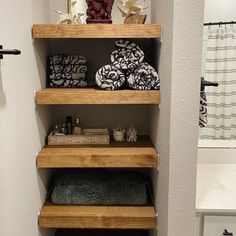 the shelves in this bathroom are made out of wood and have towels stacked on them