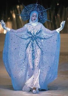 a woman dressed in blue and white with an umbrella on her head walking down a runway