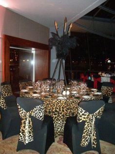 a dining room set up for a party with leopard print table cloths and black chairs